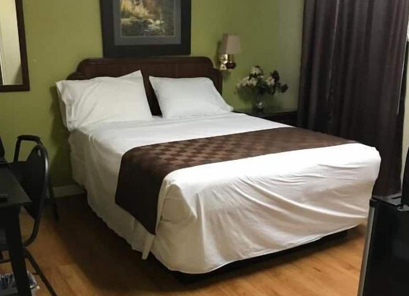 Guest bedroom with wood flooring and a curtained window