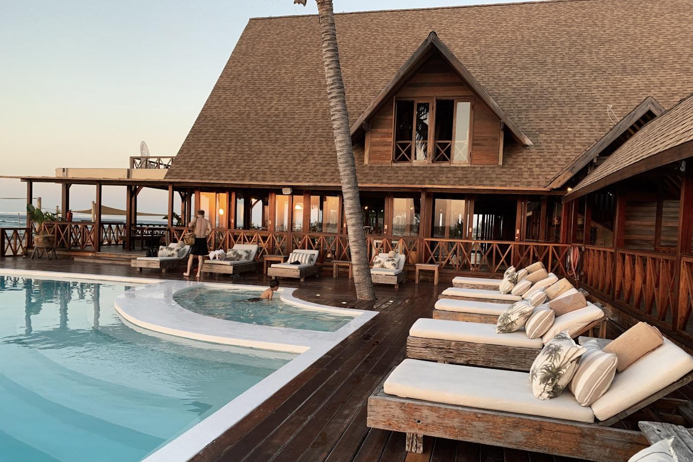 Loungers and a pool beside a timber lodge at golden hour