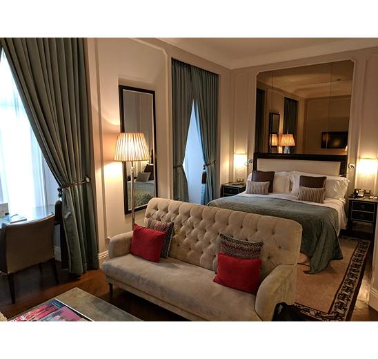 Queen bed with a sofa at the foot, lamplight and floor-length curtains