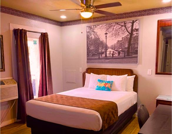 Queen room with a ceiling fan, framed canal print and a wide bed